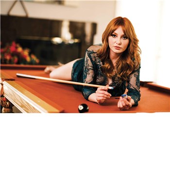 Red haired female posed laying on pool table 