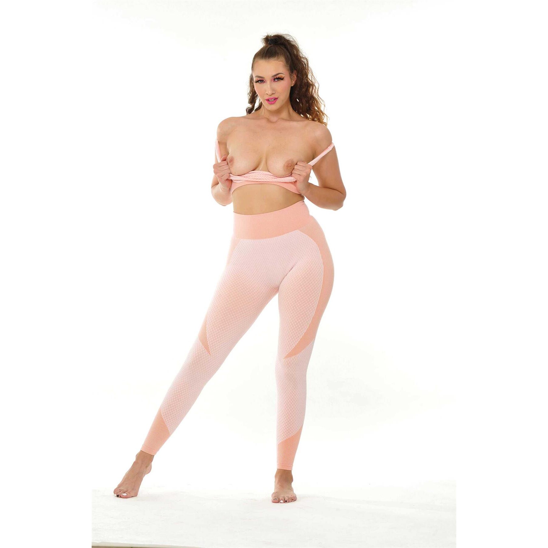 Brunette female posed topless wearing leggings displaying breasts