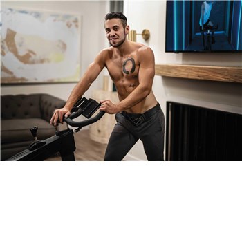 Topless male posed in front of exercise bike