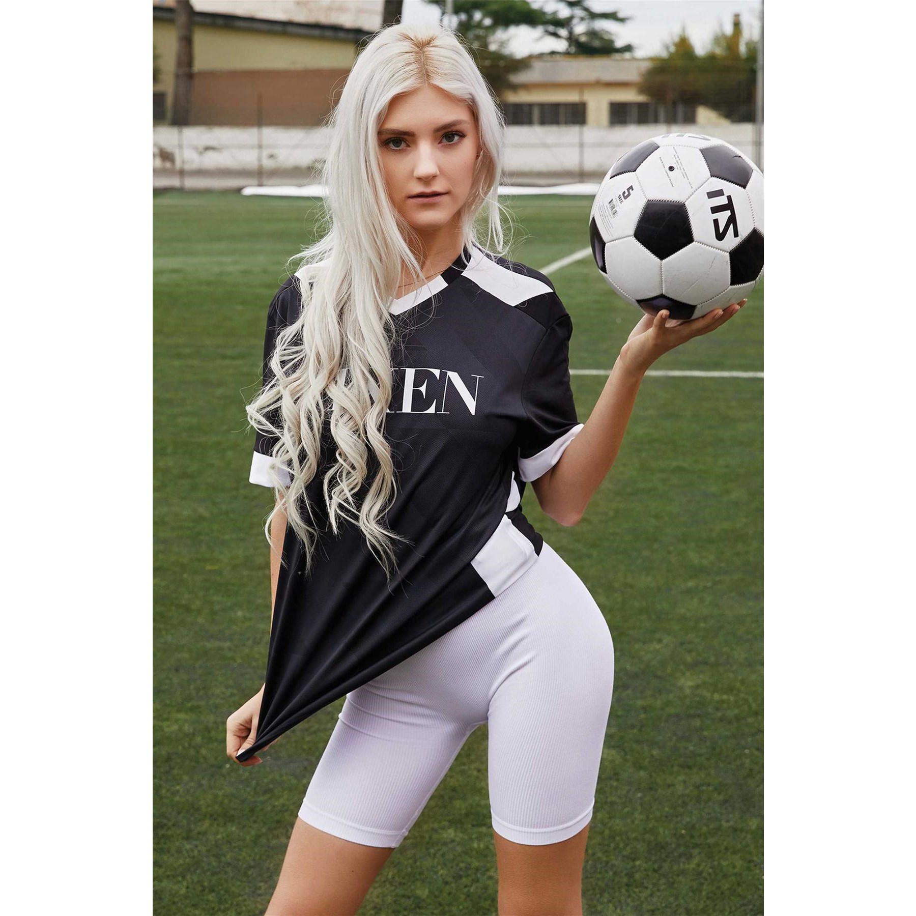 Blonde female posed wearing athletic uniform holding soccer ball