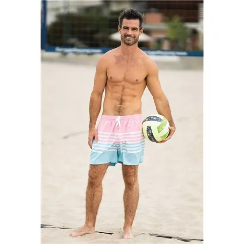 Topless male posed wearing swim trunks on beach holding volleyball