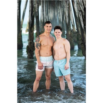 Two topless males posed on beach wearing swim trunks