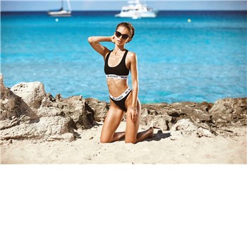 Brunette female posed on beach wearing bikini displaying cleavage
