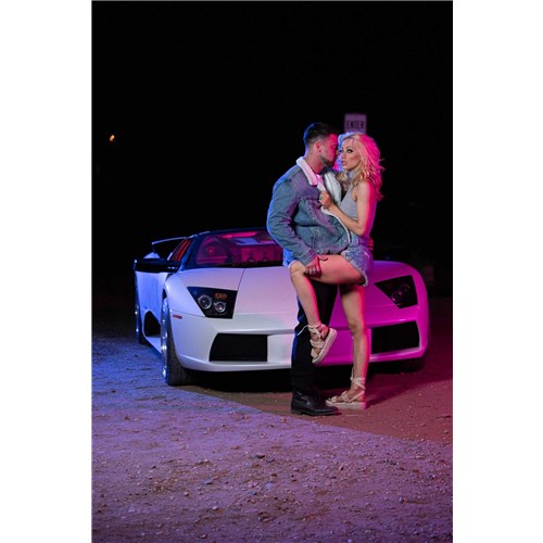Blonde female caressed by male posed by car