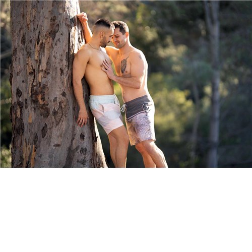 Two topless males caressing outdoors